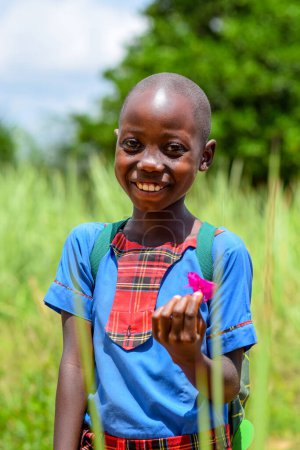 Photo for Abuja, Nigeria - June 12, 2023: Portrait of cute african school girl posing on the background of green grass - Royalty Free Image