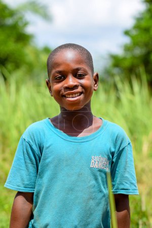 Foto de Abuja, Nigeria - 12 de junio de 2023: Retrato del niño de la escuela africana posando sobre el fondo de hierba verde - Imagen libre de derechos