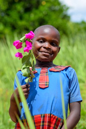 Téléchargez les photos : Abuja, Nigeria - 12 juin 2023 : Portrait d'une jolie écolière africaine posant sur le fond d'herbe verte - en image libre de droit