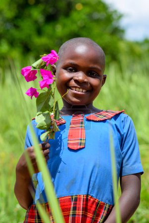 Téléchargez les photos : Abuja, Nigeria - 12 juin 2023 : Portrait d'une jolie écolière africaine posant sur le fond d'herbe verte - en image libre de droit