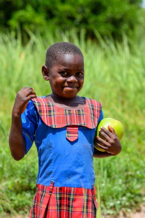 Foto de Abuja, Nigeria - 12 de junio de 2023: Retrato de una linda niña de escuela africana posando sobre el fondo de hierba verde - Imagen libre de derechos