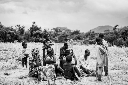 Photo for Nigeria - June 20, 2023: Group of African people with children sitting on grass, black and white - Royalty Free Image