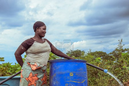 Foto de Abuja, Nigeria - 8 de octubre de 2022: Mujer africana Fetching Water. Solución de Agua Limpia en Comunidad Africana. Feliz africano fetching agua en un cubo - Imagen libre de derechos