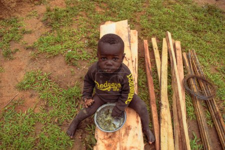 Téléchargez les photos : Opialu, Benue Etat - février 6, 2022 : African Child eating and looking at the camera. - en image libre de droit