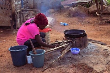 Téléchargez les photos : Opialu, Benue Etat - Mars 6, 2021 : African Woman Cooking Outdoor with a Firewood - en image libre de droit