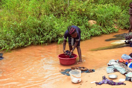 Téléchargez les photos : Delta State, Nigeria - 9 décembre 2021 : Femmes africaines lavant leurs vêtements dans un fleuve, Nigeria - en image libre de droit