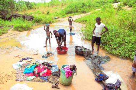 Téléchargez les photos : Delta State, Nigeria - 9 décembre 2021 : Femmes africaines lavant leurs vêtements dans un fleuve, Nigeria - en image libre de droit