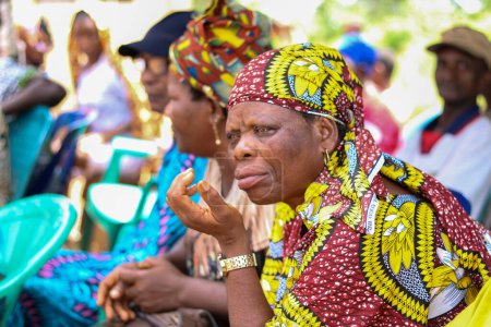 Foto de Abuja, Nigeria - 20 de diciembre de 2021: Africanos sentados mientras esperan en una cola para recibir atención médica gratuita y atención en una comunidad rural. Campaña política en África - Imagen libre de derechos