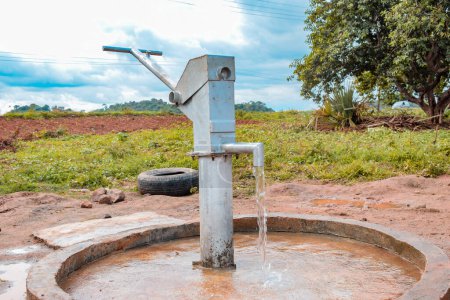 Photo for Karara, Nasarawa State, Nigeria - May 5, 2021: Newly Constructed Indian Hand Pump Borewell in a Rural Community in Africa. Running Water from a Community Borehole Water Point - Royalty Free Image