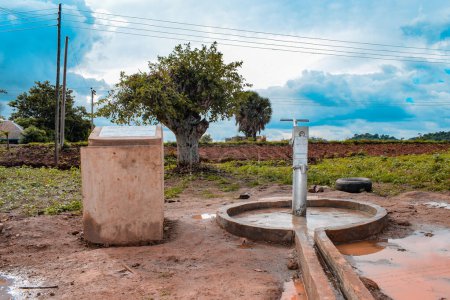 Foto de Karara, estado de Nasarawa, Nigeria - 5 de mayo de 2021: Bomba de mano india recién construida Borewell en una comunidad rural de África. Agua corriente desde un punto de agua de pozo comunitario - Imagen libre de derechos