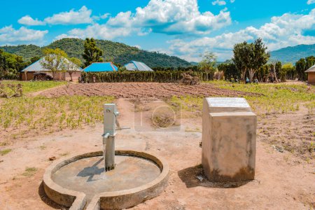 Foto de Karara, estado de Nasarawa, Nigeria - 5 de mayo de 2021: Bomba de mano india recién construida Borewell en una comunidad rural de África. Agua corriente desde un punto de agua de pozo comunitario - Imagen libre de derechos