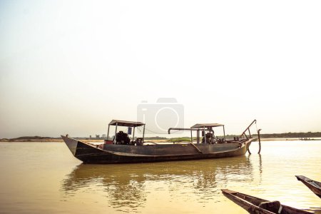 Foto de Estado del Delta, Nigeria - 9 de diciembre de 2021: Canoas hechas localmente junto a un río en el río Níger compensando un hermoso amanecer. Barcos de pesca en la orilla de un río. Reflexión sobre una superficie de agua. - Imagen libre de derechos