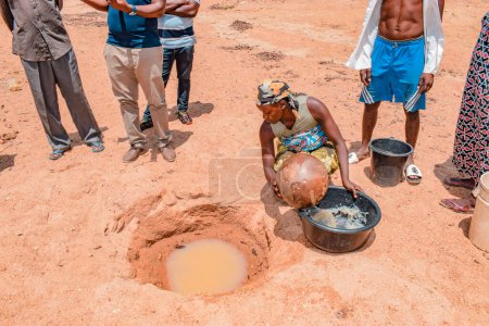 Photo for Jos East, Plateau State, Nigeria - May 12, 2021: African people Fetching Unclean and Contaminated Water from a Pond or Stream for their Daily Consumption - Royalty Free Image