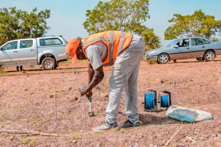 Téléchargez les photos : Jos East, État du Plateau - 12 mai 2021 : Géologue africain et membres de l'équipe menant un levé géophysique pour la disponibilité de l'eau sur le terrain. Science des sols. Projet d'eau rurale. - en image libre de droit