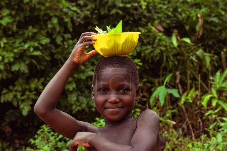 Téléchargez les photos : Abuja, Nigéria - 5 octobre 2022 : Portrait d'un enfant africain. Random Candid Moments with African Children. Fille portant bol sur la tête - en image libre de droit
