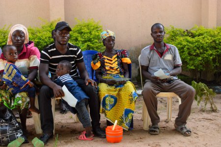 Foto de Estado de Edo, Nigeria - 10 de agosto de 2021: Africanos sentados, haciendo cola y esperando atención médica gratuita en una comunidad rural - Imagen libre de derechos