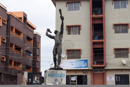 Téléchargez les photos : Enugu, Nigéria - 20 juin 2023 : Statue d'un cri de ville à un rond-point majeur entouré de bâtiments Storey Obiagwu Junction - en image libre de droit