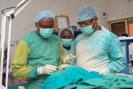 Téléchargez les photos : Abuja, Nigéria - 06 mai 2021 : Chirurgien plastique africain et membres de son équipe effectuant une intervention chirurgicale dans un théâtre médical - en image libre de droit