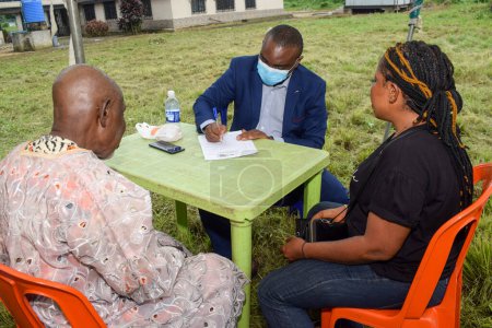 Foto de Aluu, Port Harcourt - 10 de agosto de 2021: Africanos esperan atención médica gratuita y atención en una comunidad rural. La gente se registra para votar en las elecciones. Ejercicio de campaña política - Imagen libre de derechos