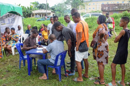 Téléchargez les photos : Aluu, Port Harcourt - 10 août 2021 : Africains en attente de soins médicaux gratuits et d'attention dans une communauté rurale. Les gens s'inscrivent pour voter aux élections. Exercice de campagne politique - en image libre de droit