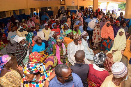 Foto de Abuja, Nigeria - 10 de octubre de 2021: Los africanos esperan en una cola para recibir atención médica y atención en una comunidad rural. Campaña política en África - Imagen libre de derechos