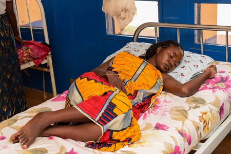 Téléchargez les photos : Kachia, État de Kaduna - septembre 6, 2021 : Un jeune Africain se remet sur un lit de malade dans une clinique rurale après une chirurgie réussie - en image libre de droit