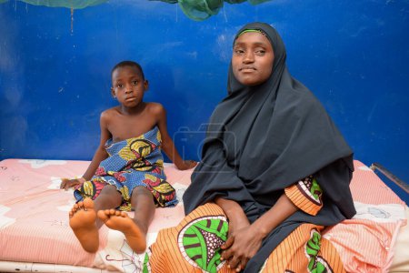 Téléchargez les photos : Abuja, Nigéria - 6 septembre 2021 : Une mère africaine prend soin de son enfant malade dans une clinique rurale - en image libre de droit