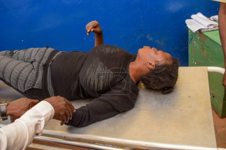 Téléchargez les photos : Lagos, Nigéria - 6 septembre 2021 : Une Africaine vêtue de noir lors de fortes douleurs est embarquée pour une opération d'urgence. Douleurs abdominales déchirantes. Appendicite rompue - en image libre de droit