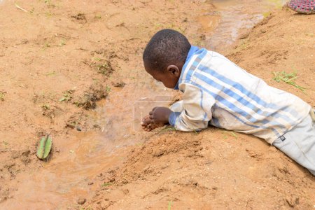 Téléchargez les photos : Abuja Nigeria - 02 août 2021 : African Child Playing with Sand on a Sunny Day. Temps d'amusement avec des enfants du tiers monde - en image libre de droit