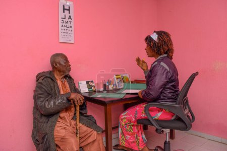 Téléchargez les photos : Abuja, Nigéria - 09 août 2021 : Le Moyen Âge visite un médecin pour une consultation oculaire en clinique rurale. Contrôle oculaire et test oculaire - en image libre de droit
