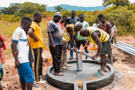 Photo for Jos East, Plateau State, Nigeria - May 12, 2021: Group of africans people working of installing hand pump water well. - Royalty Free Image