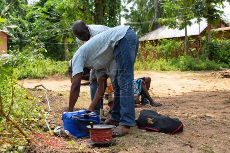 Foto de Abuja, Nigeria - 28 de octubre de 2021: Geólogos africanos y miembros del equipo realizan una encuesta geofísica sobre la disponibilidad de agua en el suelo. Ciencias y pruebas del suelo. Proyecto Agua Rural. - Imagen libre de derechos
