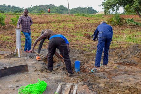 Téléchargez les photos : Jos East, État du Plateau, Nigéria - 12 mai 2021 : Installation d'une pompe à main dans les communautés rurales. Objectifs des ODD au Nigeria Afrique. Groupe de personnes africaines travaillant à l'installation d'une pompe à main puits d'eau. - en image libre de droit