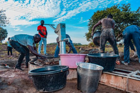 Foto de Jos East, Plateau State, Nigeria - 12 de mayo de 2021: Instalación de pozos de agua con bomba manual en comunidades rurales. Objetivos de los ODS en Nigeria África. Grupo de africanos que trabajan en la instalación de pozo de agua bomba de mano. - Imagen libre de derechos