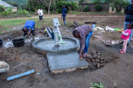 Foto de Jos East, Plateau State, Nigeria - 12 de mayo de 2021: Grupo de africanos que trabajan en la instalación de pozos de agua con bomba manual. - Imagen libre de derechos