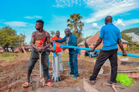 Foto de Jos East, Plateau State, Nigeria - 12 de mayo de 2021: Grupo de africanos que trabajan en la instalación de pozos de agua con bomba manual. - Imagen libre de derechos