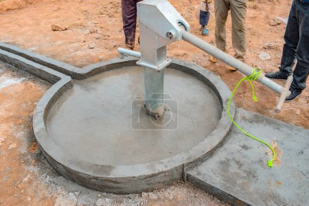 Photo for Jos East, Plateau State, Nigeria - May 12, 2021: Group of africans people working of installing hand pump water well. - Royalty Free Image