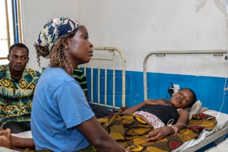Téléchargez les photos : Opialu, État de Benue - 6 mars 2021 : Une mère africaine prend soin de sa fille malade dans une clinique rurale - en image libre de droit