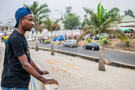 Photo for Nigeria - June 20, 2023: young man looking at African town - Royalty Free Image