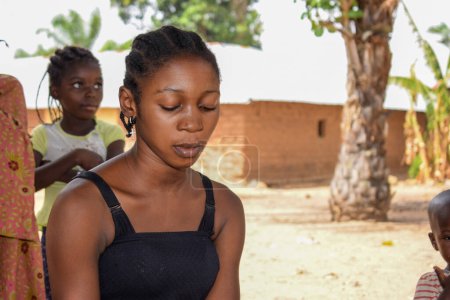 Téléchargez les photos : Karara, État de Nasarawa - Mai 5, 2021 : African Teen Cracks Groundnut Shell in a Rural Community - en image libre de droit