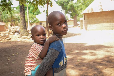 Téléchargez les photos : Karara, État de Nasarawa - 5 mai 2021 : Portrait d'un enfant africain portant son frère sur le dos - en image libre de droit