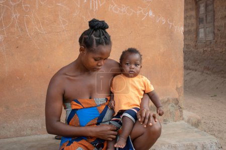 Téléchargez les photos : Opialu, Benue Etat - Mars 6, 2021 : African Mother Sitting Outdoor Tending to her Child - en image libre de droit