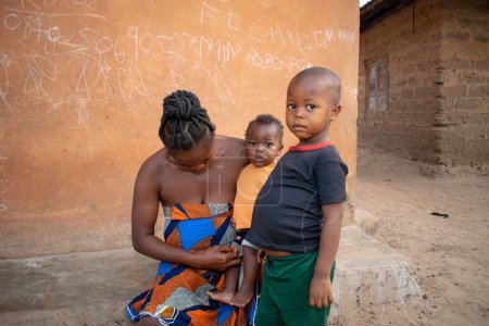 Téléchargez les photos : Opialu, Benue Etat - Mars 6, 2021 : African Mother Sitting Outdoor Tending to her Children - en image libre de droit