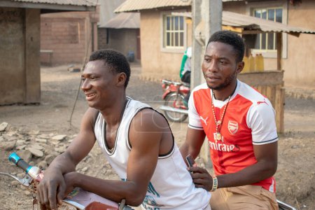 Téléchargez les photos : Opialu, État de Benue, Nigéria - 6 mars 2021 : portrait de deux hommes africains assis à vélo - en image libre de droit