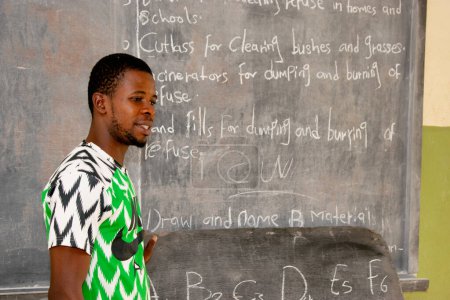Foto de Opialu, estado de Benue, Nigeria - 6 de marzo de 2021: Profesor africano enseñando a sus estudiantes inglés en una comunidad rural - Imagen libre de derechos