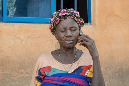 Photo for Opialu, Benue State - March 6, 2021: Middle-Aged African Woman talking on phone - Royalty Free Image