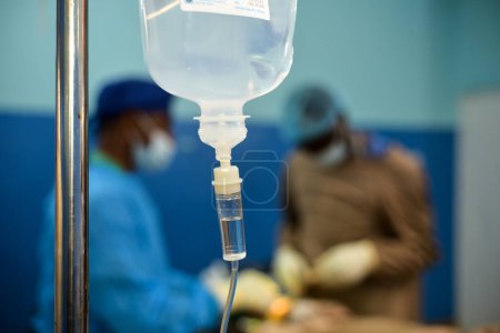 Téléchargez les photos : Abuja Nigeria - July 7, 2023: African Plastic Surgeons in a soft focus blue background. Normal Saline IV infusion prepared for surgery. - en image libre de droit