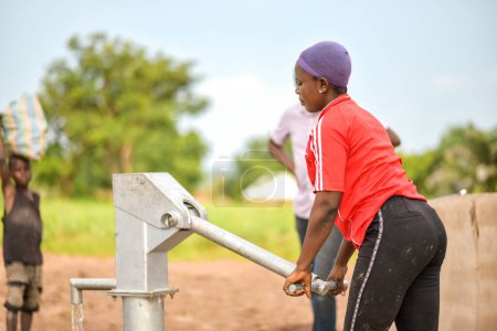 Photo for Talata, Plateau State - April 2, 2023: Indigenous African woman Fetching Water from a Newly Built Indian Hand Pump. Community Members Fetching Water for Domestic Use. - Royalty Free Image