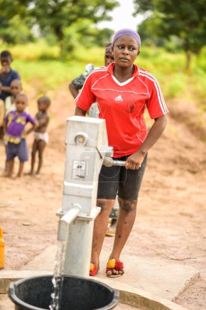 Téléchargez les photos : Talata, État du Plateau - 2 avril 2023 : Une femme africaine autochtone récupère l'eau d'une pompe à main indienne nouvellement construite. Les membres de la communauté vont chercher de l'eau pour usage domestique. - en image libre de droit