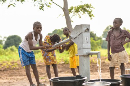 Foto de Talata, Plateau State - 2 de abril de 2023: Niños indígenas africanos que buscan agua de una bomba de mano india recién construida. Miembros de la comunidad que buscan agua para uso doméstico. - Imagen libre de derechos